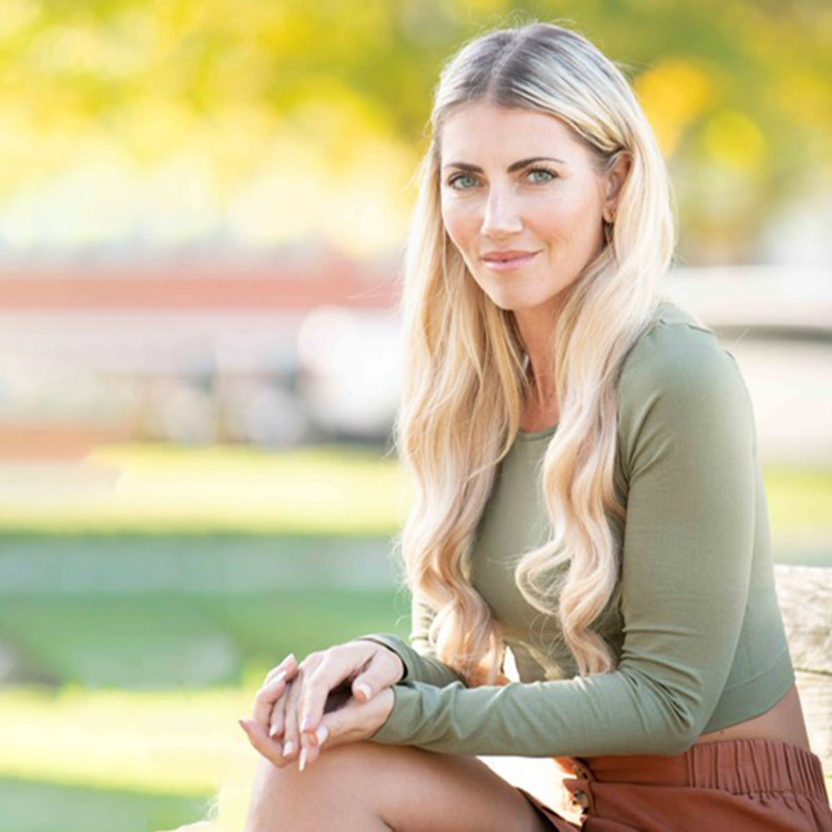 blonde haired women sitting with hands on knees wearing a long sleeve crop top in the color safari