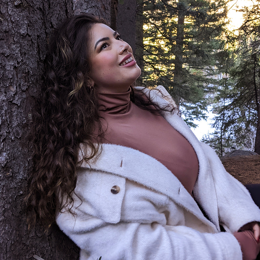 Woman Standing Next To A Tree Wearing A Copper Turtleneck