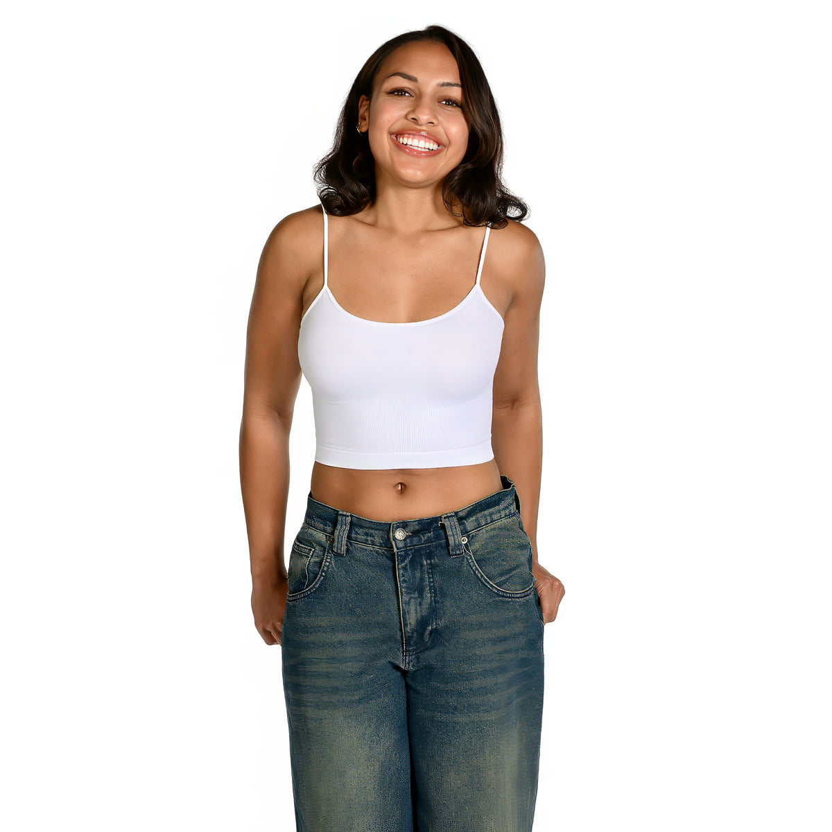 A smiling woman wearing a white spaghetti-strapbralette and blue jeans, standing against a solid white background.