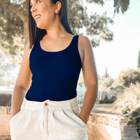 Woman wearing a Navy Basic Tank Top hand in pockets of ivory pants