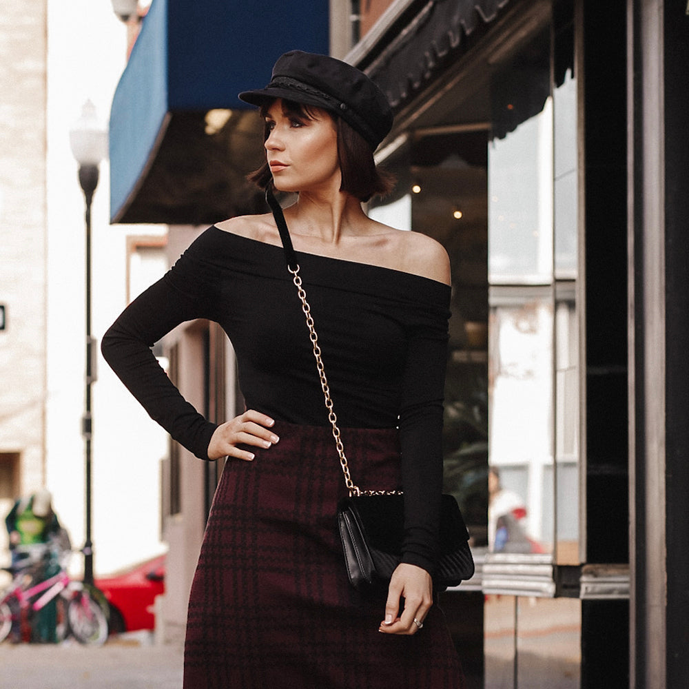 Woman wearing the Black Boat Neck Top  standing outside on the street carrying a crossbody purse