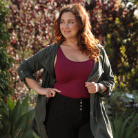 Woman standing in front of trees wearing a cranberry plus basic tank top