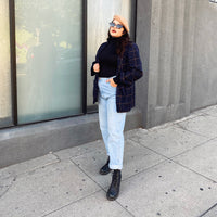 Woman Next To A Building With A Hand In Her Pocket Wearing A Black Turtleneck And Beret
