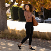 Woman Walking Outside Holding A Tote Wearing A Copper Turtleneck