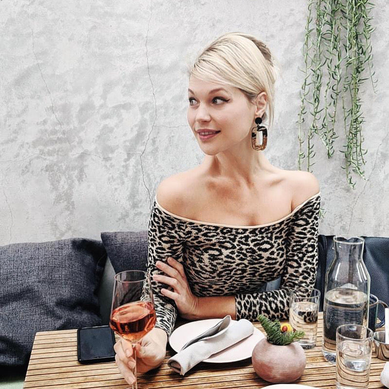 Woman sitting at an outdoor restaurant drinking wine wearing a Leopard Stone 3/4 Sleeve Animal Print Tee